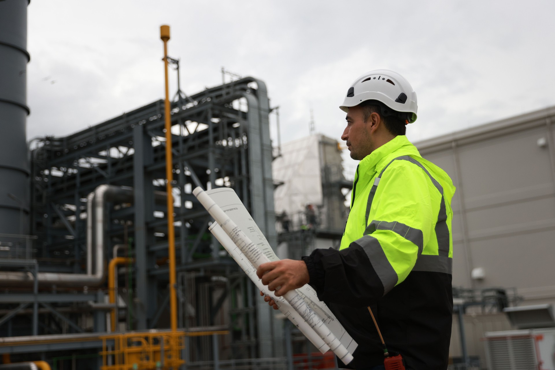 System  engineer with glow green safety jacket holds blueprint drawing at Thermal  Power plant power manufacturing site